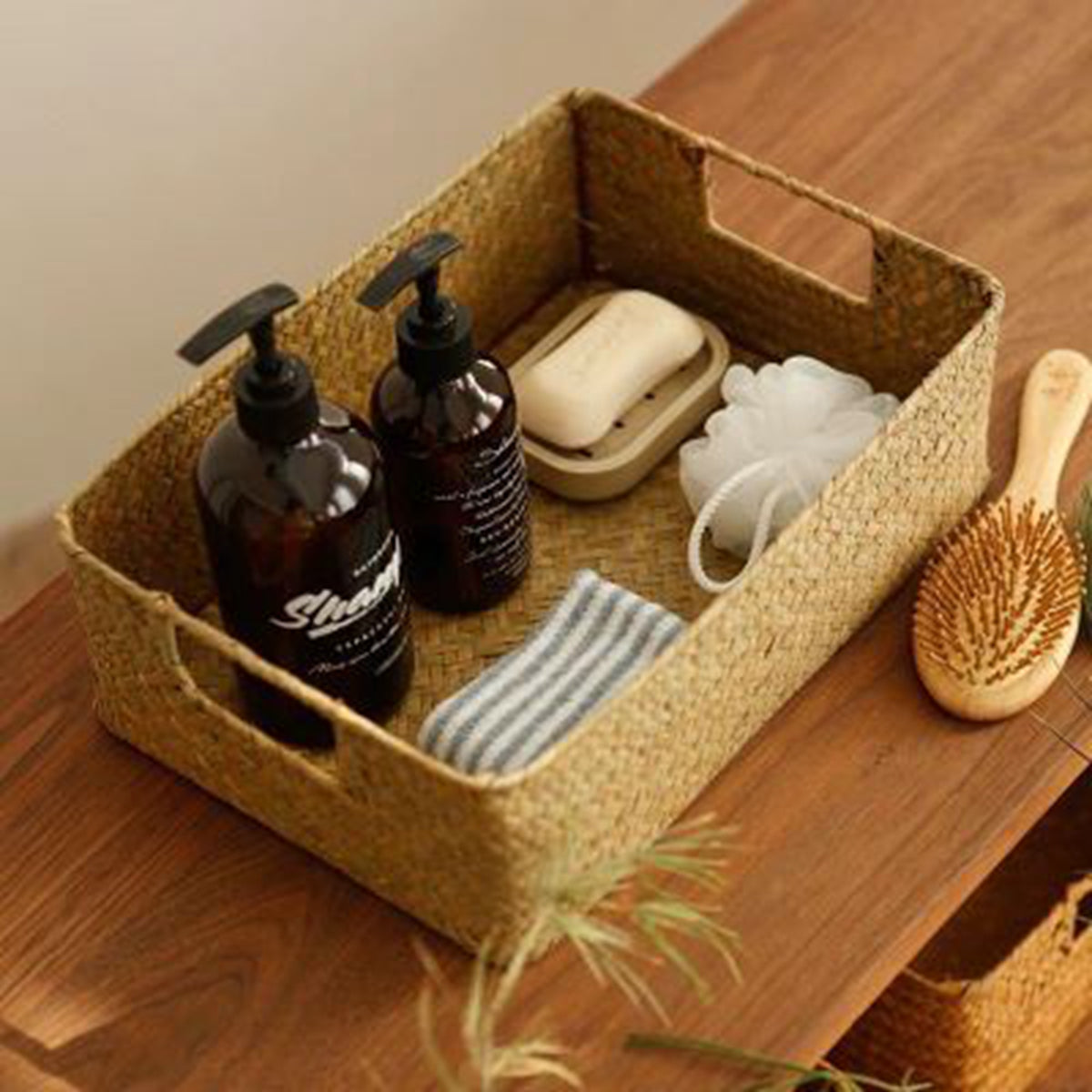 Woven basket on a wooden surface with bath products including bottles, soap, and a scrubber.